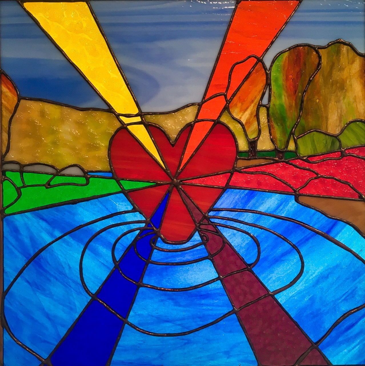 A red Heart emanating the spectrum of rays, as it hovers over a river, creating ripples, with mountains and trees in the background.