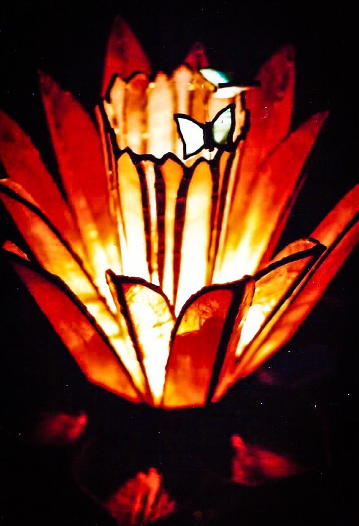 Stained glass lamp resembling a lotus flower, with two blue butterflies over the center. Dark background