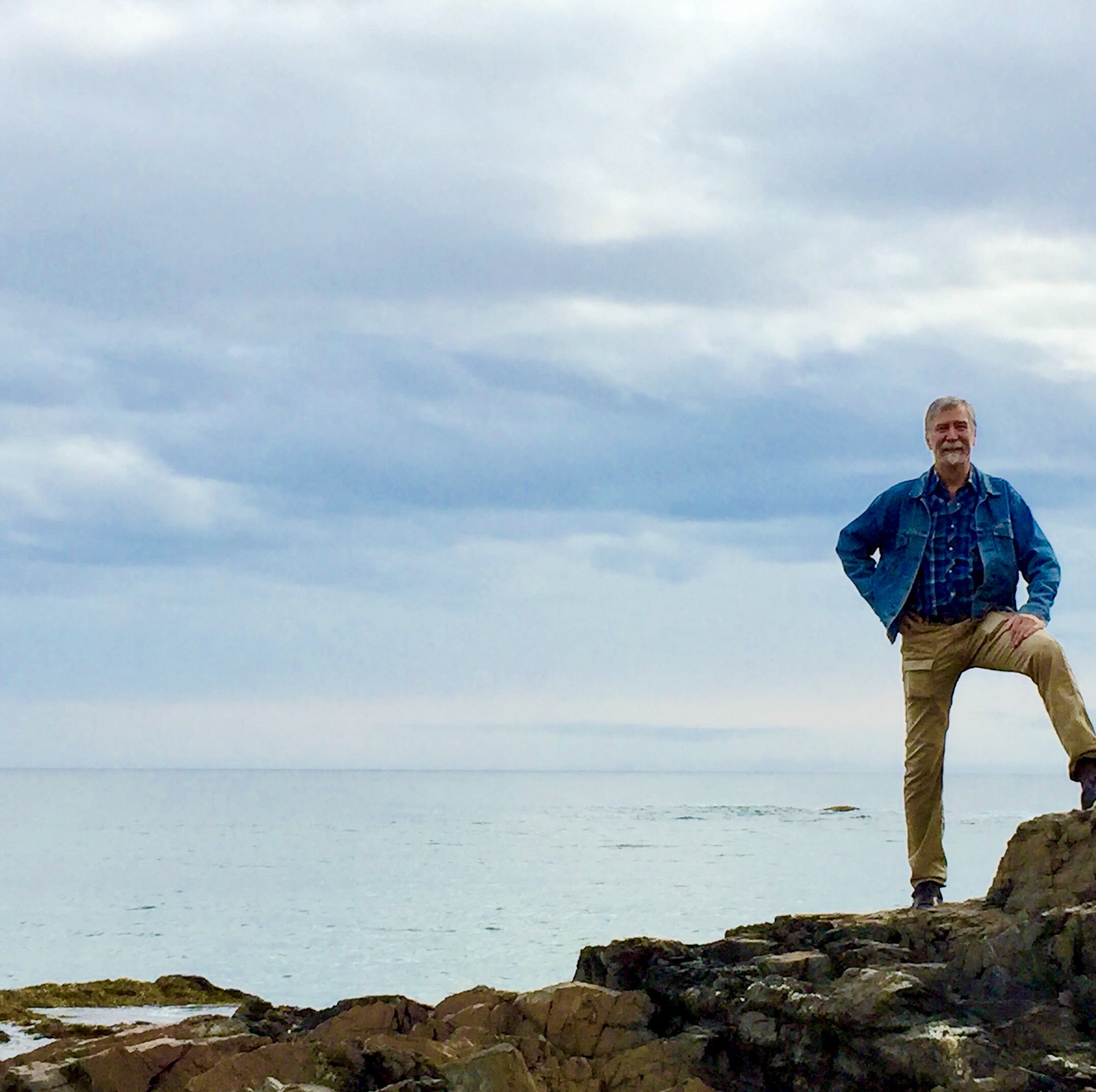 Andy, standing astride rocky shoreline, Captain Morgan(ish) pose.