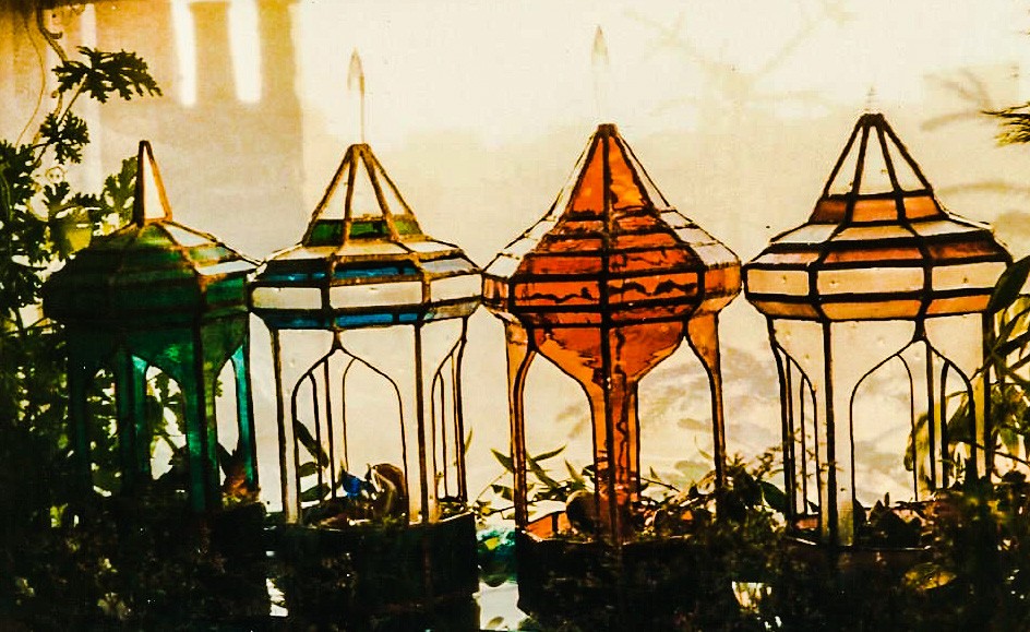 series of 4 stained glass Minaret style terrariums in a row; in green, blue/green, amber, and pinks.