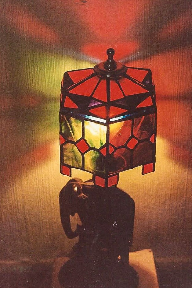 Stained glass lamp on teak elephant base. Shade resembles multi-colored umbrella.