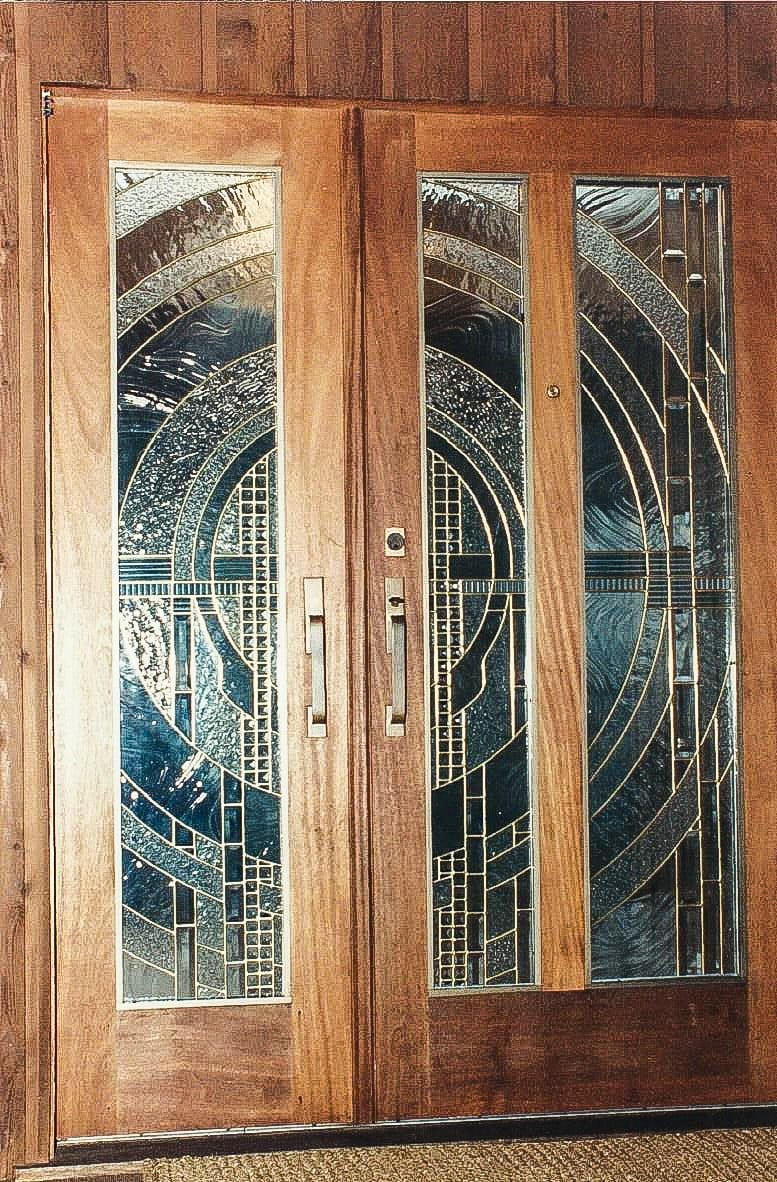 Three vertical front door panels reminiscent of Frank Lloyd Wright designs in stained glass.